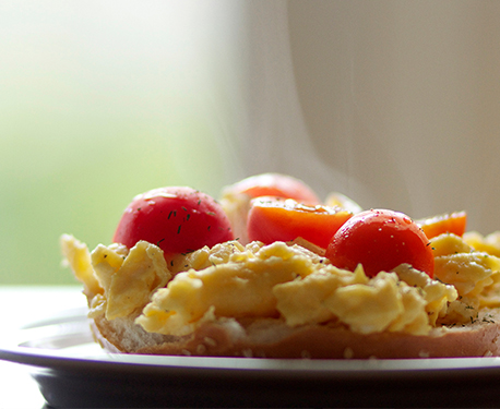 Image of bagel topped with scrambled eggs and tomatoes