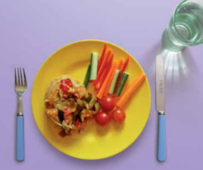 Jacket potato with vegetable filling on a plate with cutlery and glass of water. 