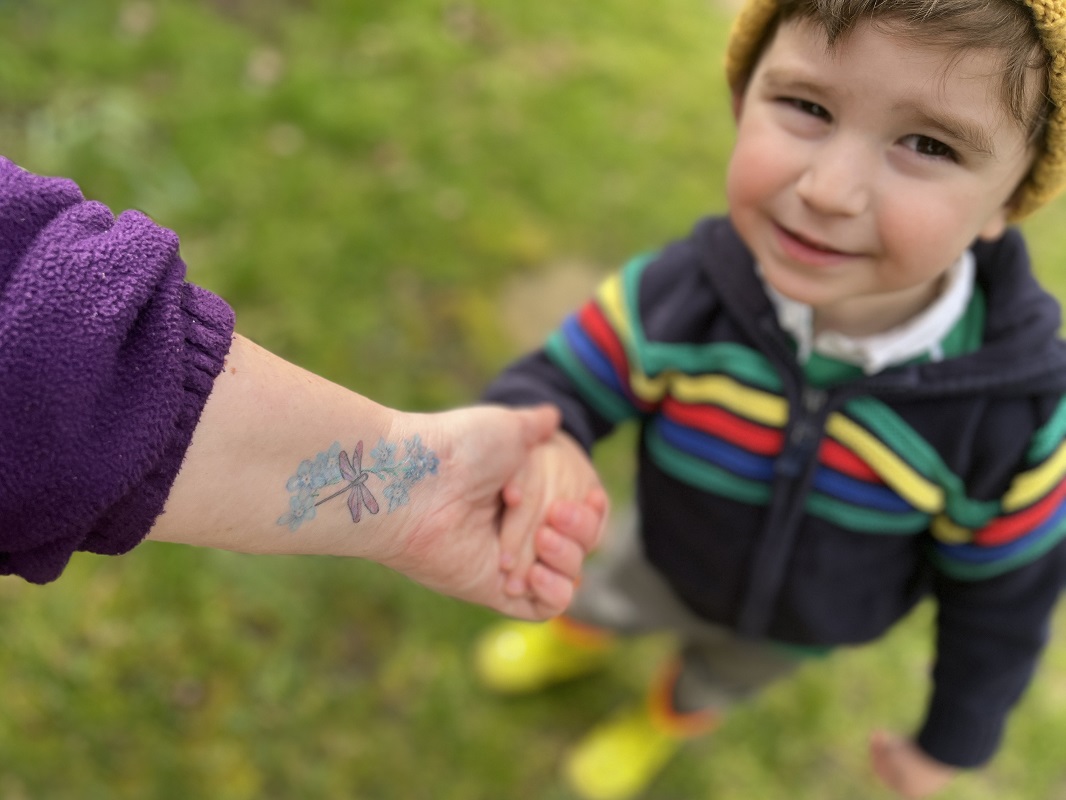 Close-up of Cairis tattoo of forgetmenots and a dragonfly