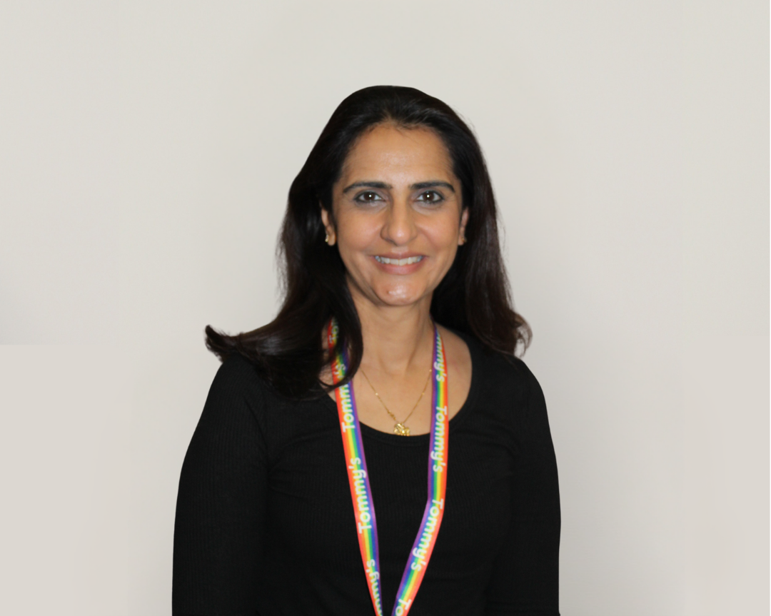 Jyotsna is smiling at the camera, wearing a rainbow lanyard.