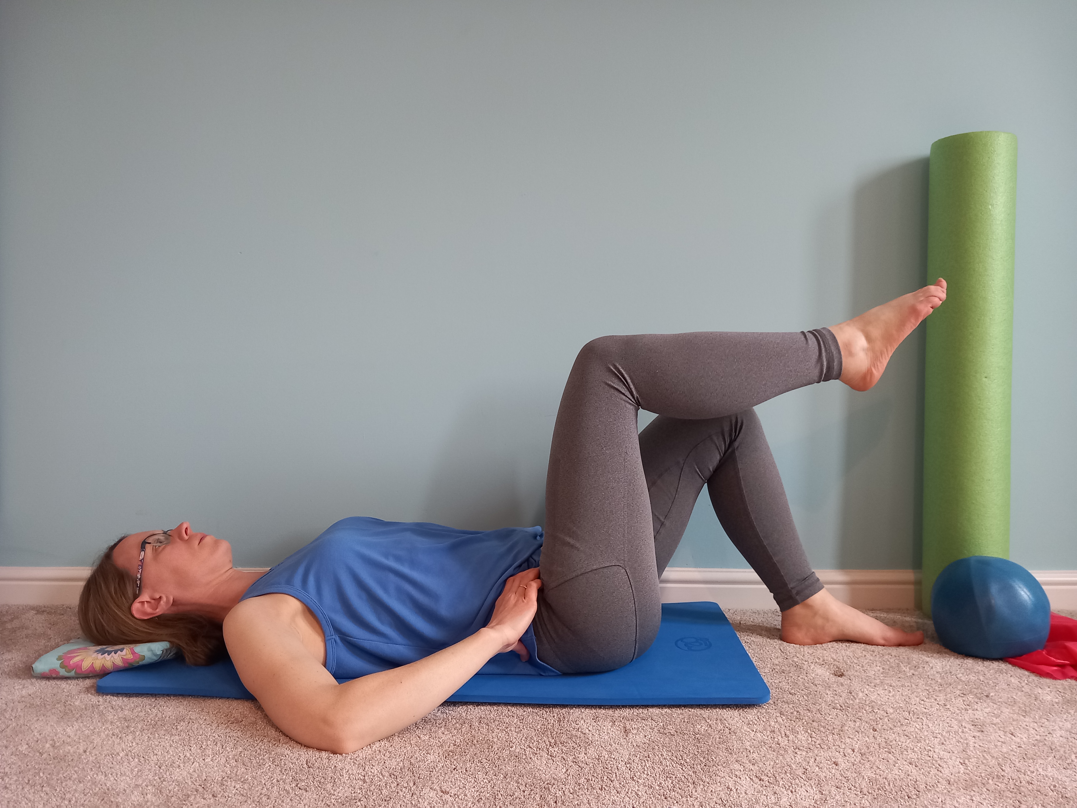 woman lying down with legs lifted practising pilates