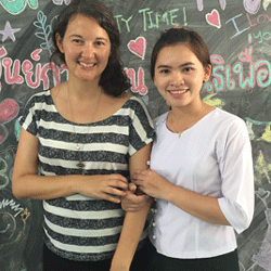 A photo of two women standing in front of a blackboard filled with colourful writing