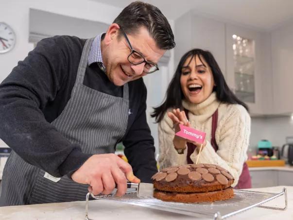 Two happy people cutting in to a chocolate cake