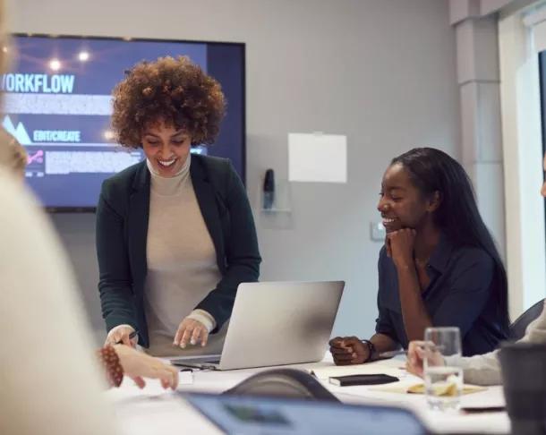 Pregnant woman doing a presentation to a table full of clients and colleagues